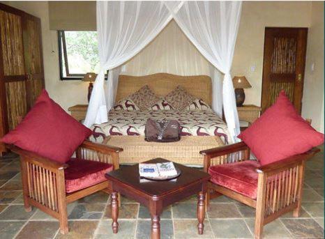 a bedroom with a bed with two chairs and a table at Metsi Lodge in Welgevonden Game Reserve