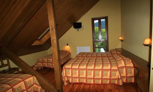 a attic bedroom with two beds and a staircase at Hotel, Bungalows y Camping Viu in Víu