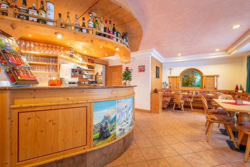 a restaurant with a bar with tables and chairs at Villa Clara in Canazei