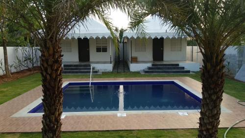 a villa with a swimming pool between two palm trees at 16 Bedouin Private Pool Villa in Hosūr
