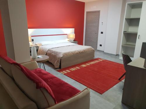 a bedroom with a bed and a red wall at Erasmus Hotel in Gela
