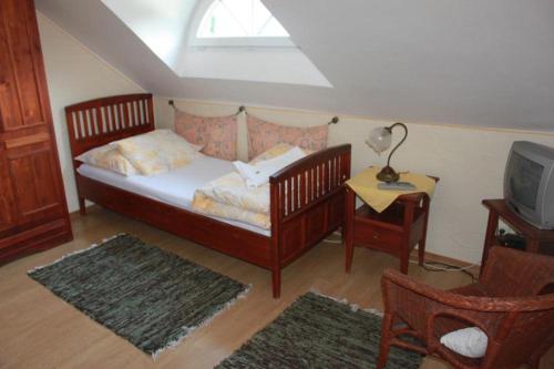 a bedroom with a bed and a tv and a chair at Pension Brusenka in Bystřice pod Hostýnem
