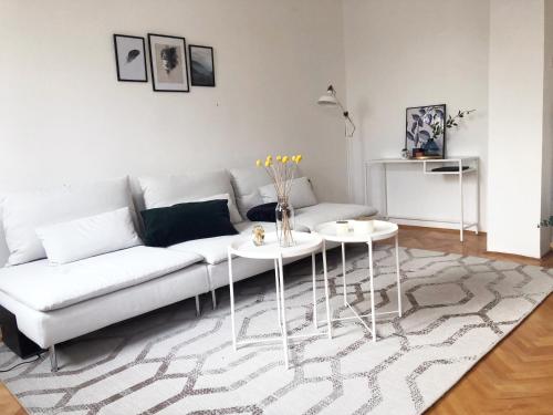 a living room with a white couch and two tables at Alva Apartment in Niš