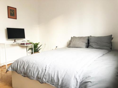 a bedroom with a white bed and a computer monitor at Alva Apartment in Niš