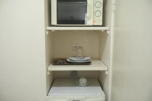 a small kitchen with a microwave and a coffee maker at Residence Hotel Carmel Cocody in Abidjan