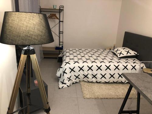 um quarto com uma cama, um candeeiro e uma mesa em Studio 104 em Mantes-la-Jolie