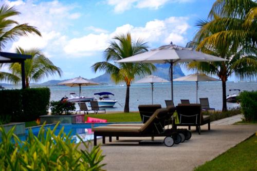 a group of chairs and umbrellas next to the beach at L'Escale 3 bedrooms Sea View and Beachfront Suite by Dream Escapes in Tamarin
