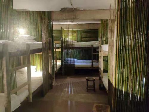 a room with three bunk beds and a table and a stool at Green Hostel & Sunny Guesthouse in Yuanyang
