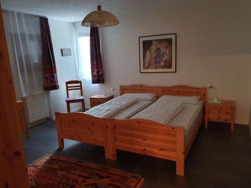 1 dormitorio con cama de madera y silla en Alpen-fewo, Denter Vias 10, Casa Alma en Flims