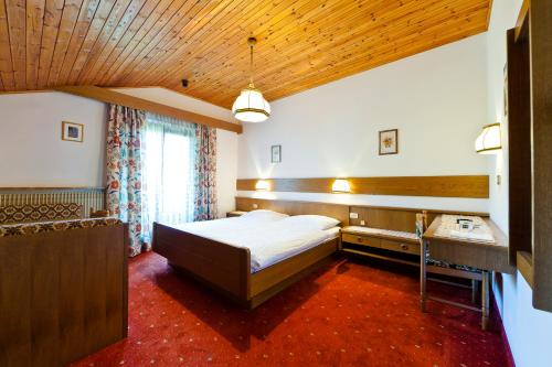 a bedroom with a bed and a desk in it at Hotel Brückenwirt - Al Ponte in Montagna