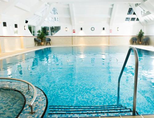 a swimming pool with blue water in a building at Crown Hotel Wetheral in Carlisle