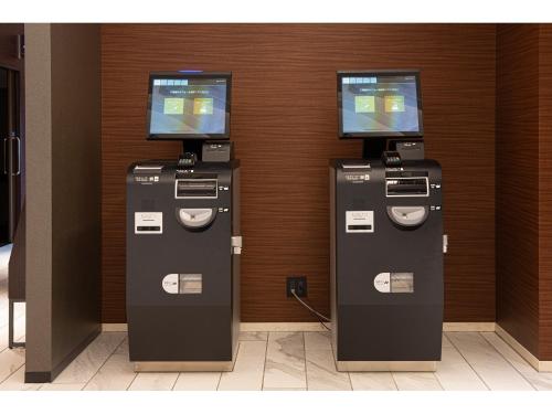 two atm machines sitting next to a wall at Place Hotel Ascot in Kumamoto