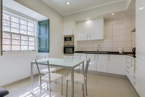 a kitchen with white cabinets and a table and chairs at Faro Tradicional House - City center in Faro