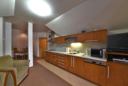a kitchen with wooden cabinets and a microwave and a tv at Apartmán Bílé Labe in Špindlerův Mlýn