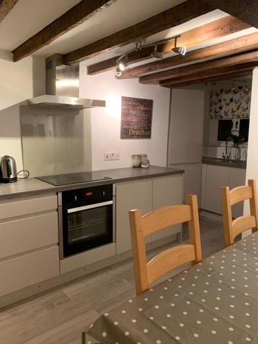 a kitchen with a stove and a table with chairs at Appletree Cottages in Mildenhall