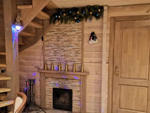 a fireplace in a living room with a christmas decoration at Holiday House & Sauna in Druskininkai in Neravai