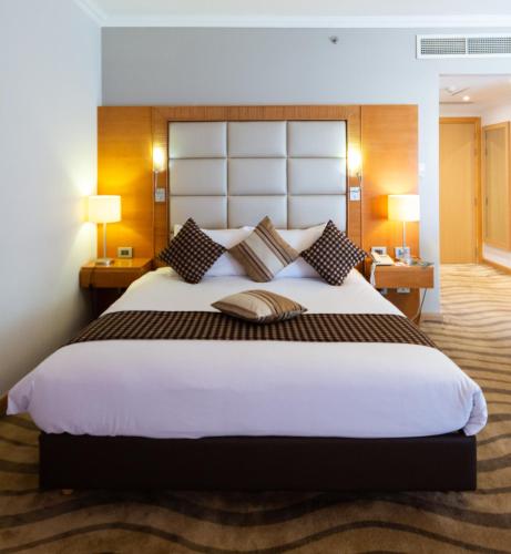 a large bed in a hotel room with two lamps at Mercure Ismailia Forsan Island in Ismailia
