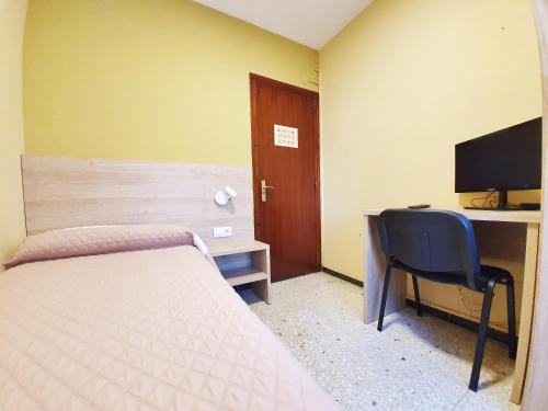 a bedroom with a bed and a desk and a television at Pensión Belmonte II in Benicarló