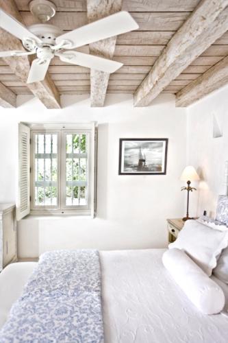 a white bedroom with a ceiling fan and a bed at Hotel Casa Quero in Cartagena de Indias