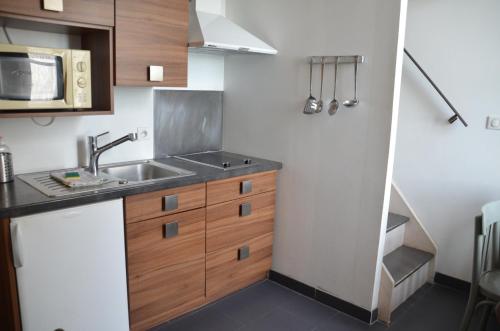 uma pequena cozinha com um lavatório e um micro-ondas em Le Mole (Appartements et Chambres) em La Flotte