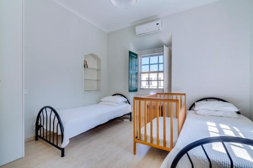 a bedroom with two beds and a crib at Faro Tradicional House - City center in Faro