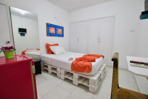 ein Schlafzimmer mit einem Bett mit einer orangefarbenen Decke in der Unterkunft QuillaHost Guesthouse in Barranquilla