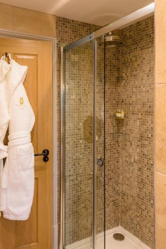 a shower in a bathroom with a robe on the door at Crossbasket Castle, Hotel & Restaurant in High Blantyre