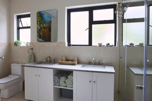 a bathroom with two sinks and a toilet at One Above in Cape Town
