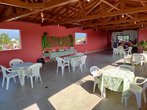 a room with tables and chairs in a room with red walls at Oásis Pousada in Bertioga