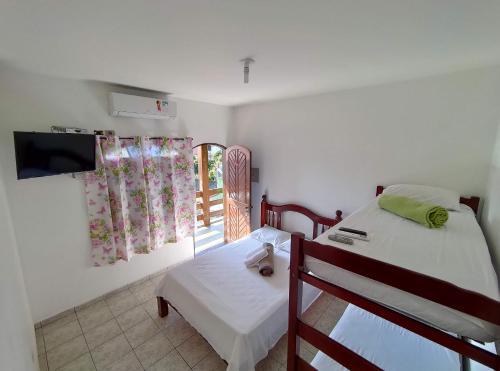 a bedroom with a bed and a tv and a window at Oásis Pousada in Bertioga