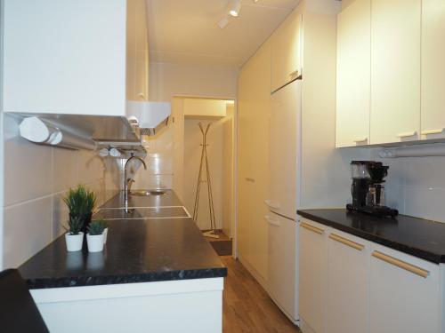 a kitchen with white cabinets and a black counter top at Apartment Oulu station II in Oulu