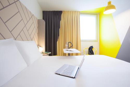 巴黎的住宿－巴黎馬塞納奧林匹茲宜必思尚品酒店，坐在酒店房间床上的笔记本电脑