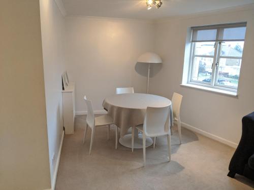 a dining room with a table and chairs and a window at Fitzroy Chiswick Apartment in London