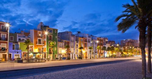 a city street with buildings and palm trees at night at Segunda casa de Ana Lucia en la playa in Villajoyosa