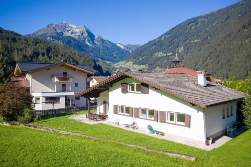 a white house with mountains in the background at Ahorn Chalet in Mayrhofen