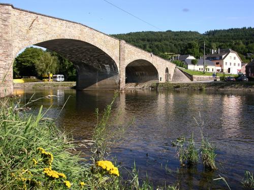 a stone bridge over a river in a town at B&B La Belle Histoire Laforêt in Laforêt