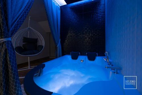 Baño azul con bañera y silla en Exclusive Apartment Centrum en Wadowice