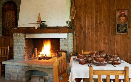 Habitación con chimenea y mesa con platos y cuencos. en Guest House Zarkova Kushta en Zheravna