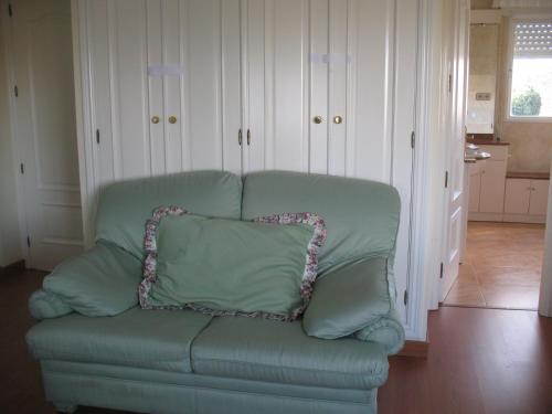 a green couch with a pillow on it in a living room at Residencial Playa Lisa in Boadilla del Monte