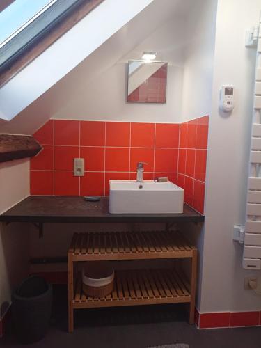 La salle de bains est pourvue d'un lavabo et d'un mur en carrelage rouge. dans l'établissement Le 3 de Gussignies, à Gussignies