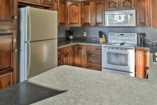 a kitchen with a white refrigerator and wooden cabinets at East Tawas Apartment Near Lake Huron and Downtown! in East Tawas