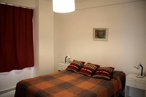 1 dormitorio con 1 cama con 2 almohadas rojas en Luminoso departamento de dos ambientes externo en Mar del Plata