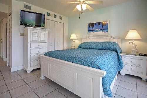 a bedroom with a bed with a blue comforter and a tv at Sanibel Island Studio with Pool Access Walk to Beach in Sanibel