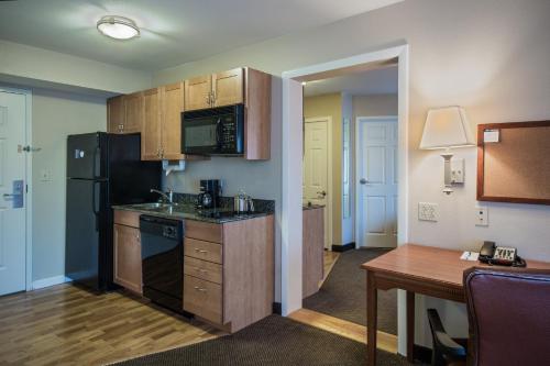 a small kitchen with a black refrigerator and a table at Candlewood Suites Windsor Locks by IHG in Windsor Locks