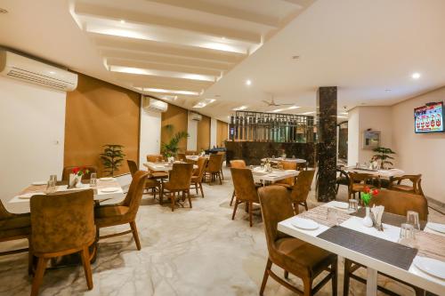 a restaurant with tables and chairs in a room at Hotel Almati Inn at Delhi Airport in New Delhi