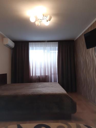 een slaapkamer met een bed en een raam met gordijnen bij Аппартаменты на Бутырина in Krementsjoek