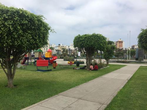 dos personas sentadas en el césped en un parque en Dormitorio Independiente en Lima