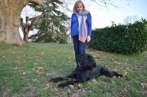 a woman standing next to a black dog in the grass at Le Platane in Lafrançaise