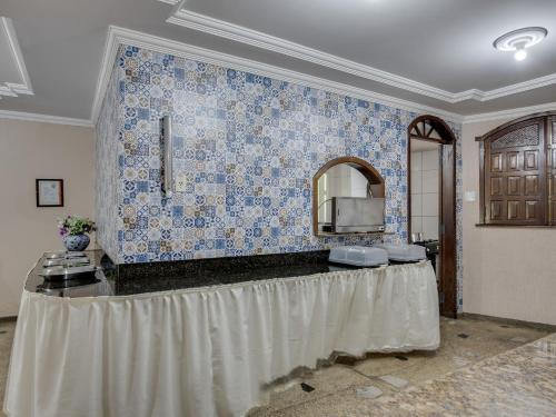 a room with a table with a mirror and blue tiles at Hotel Estrela Do Vale in Ipatinga