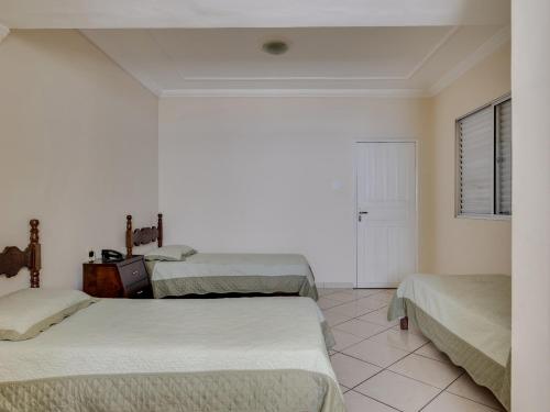 a room with three beds and a window and a door at Hotel Estrela Do Vale in Ipatinga
